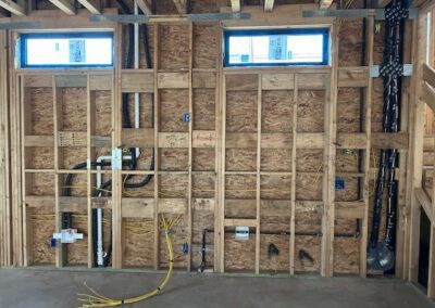 Exposed framework and wiring in a partially constructed building interior, with visible wooden studs and electrical cables.