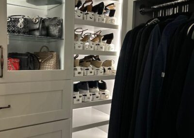 A well-organized closet with shelves of handbags, rows of shoes, and hanging clothes.