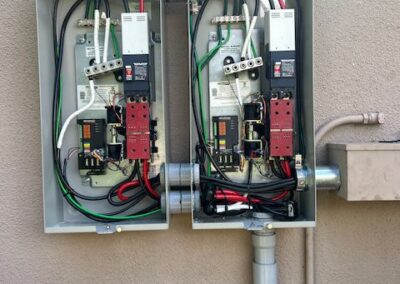 Two open electrical panels on a wall, displaying various wires, switches, and components inside.